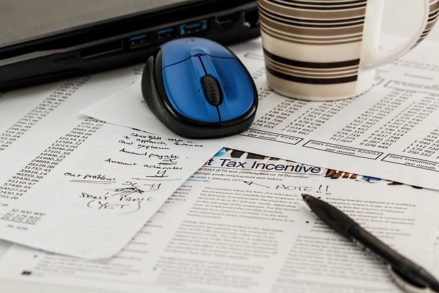 mouse and coffee on top of scattered and marked up tax forms 